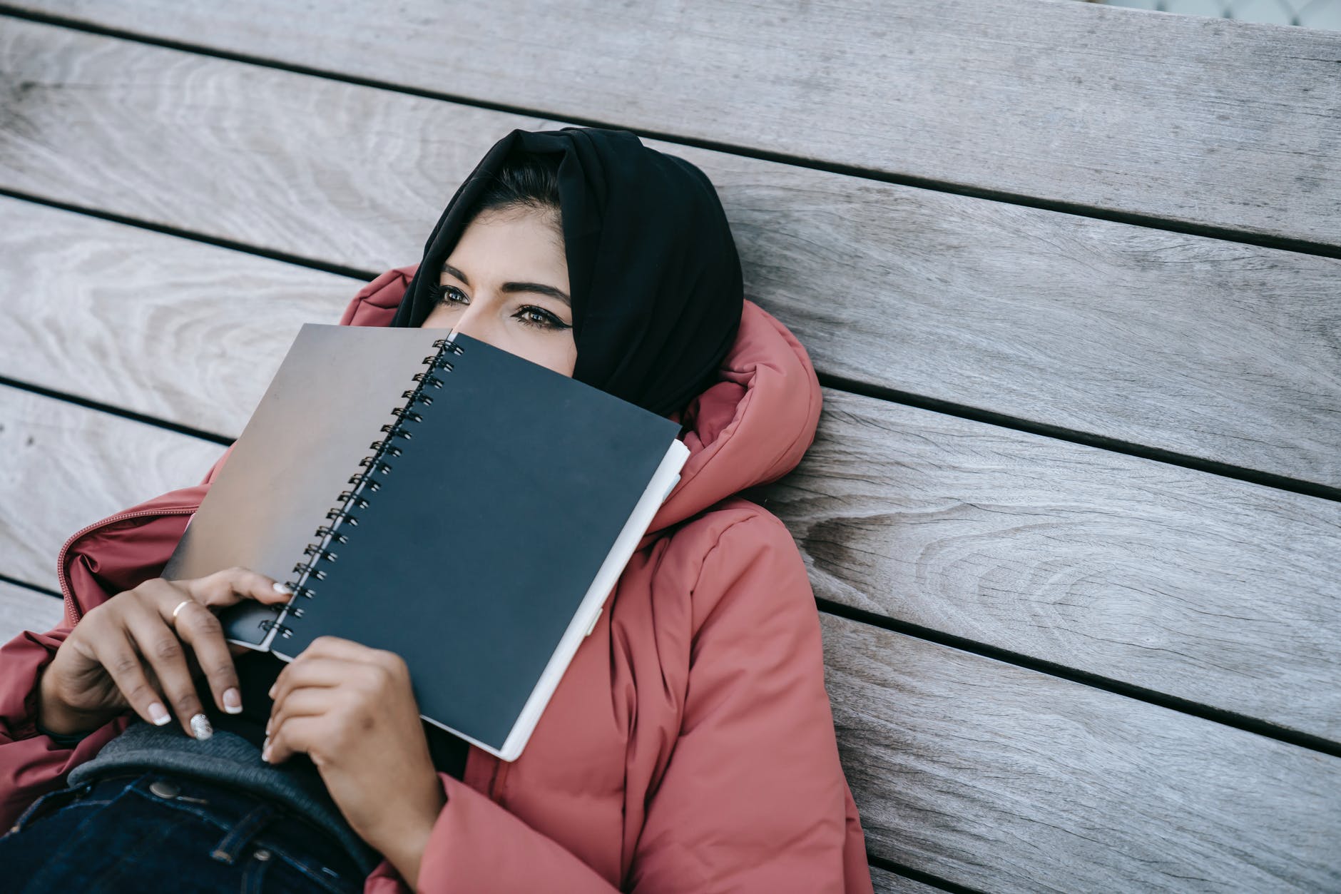tired student resting on terrace covering face with notepad