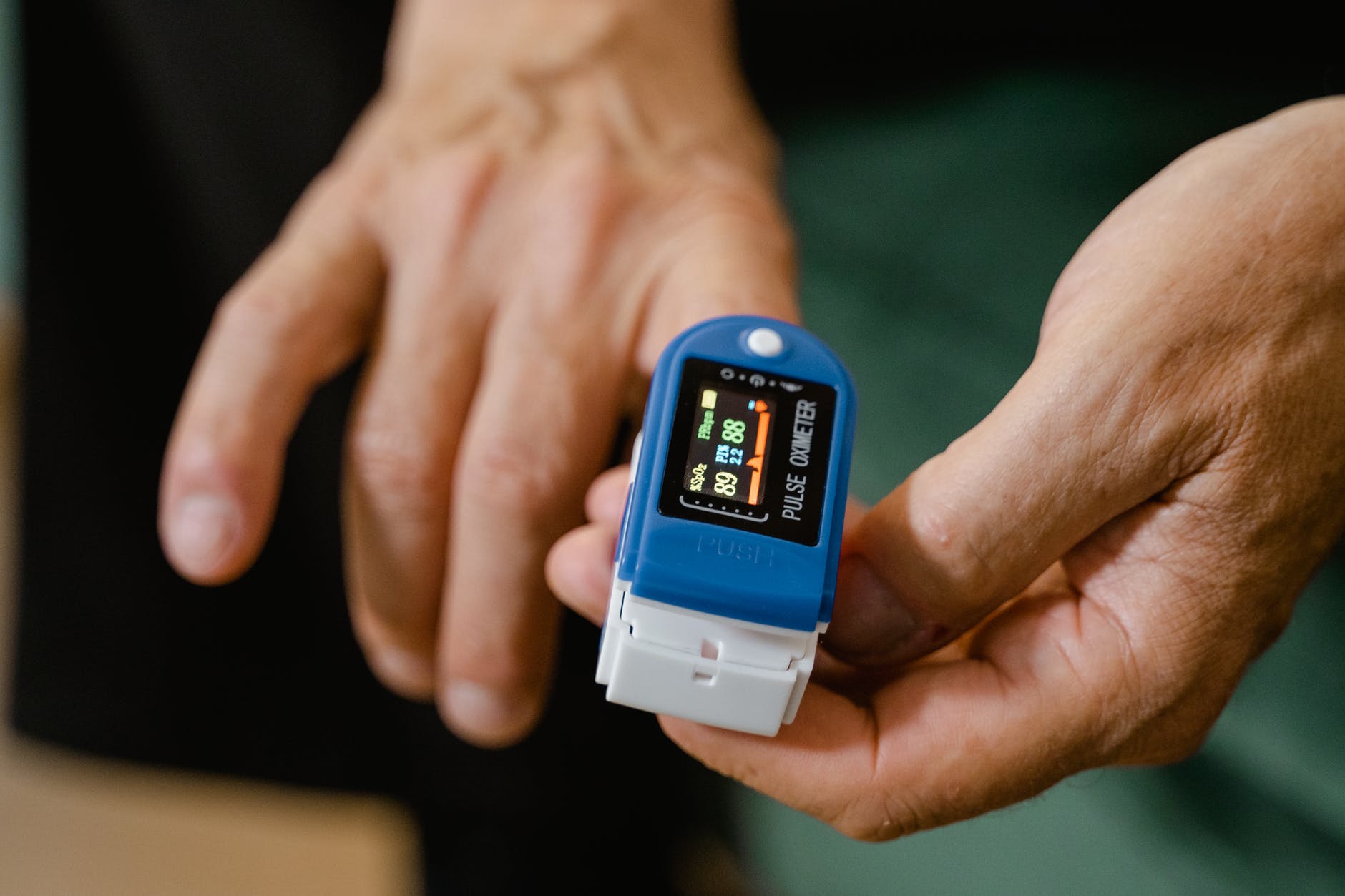 person holding blue pulse oximeter